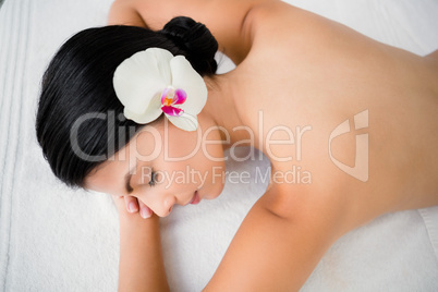 Pretty brunette enjoying a massage with flower in her hair