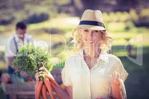 Blonde woman holding a bunch of carrots