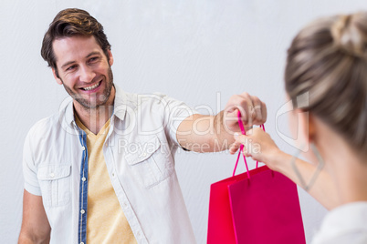 Smiling cashier giving shopping bag to woman