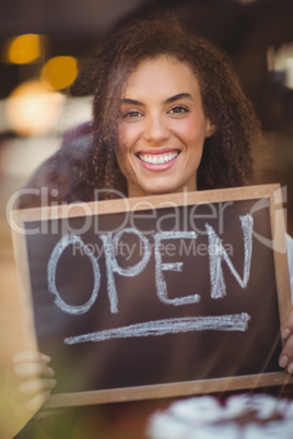 Smiling waitress showing chalkboard with open sign