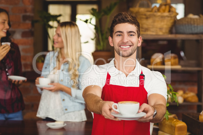 Handsome waiter handing a cup of coffee