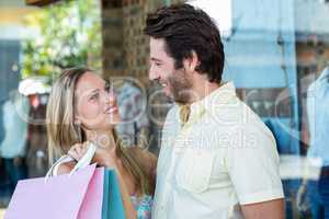 Smiling couple with shopping bags looking at each other