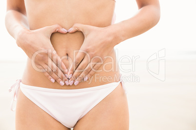 Fit woman making heart shape on belly