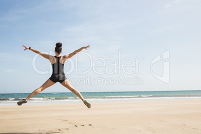 Fit woman leaping on the sand