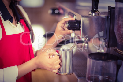 Barista steaming milk at the coffee machine