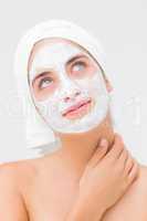 Thoughtful woman having white cream on her face