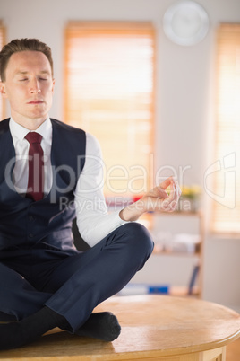 Calm businessman meditating in lotus pose