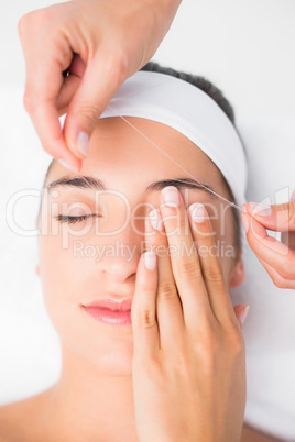 Hands threading beautiful womans upper eyes