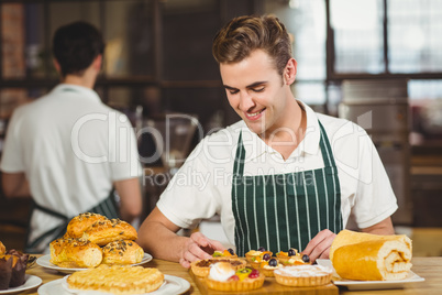 Smiling waiter tidying up the pastries