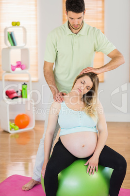 Pregnant woman having relaxing massage while sitting on exercise