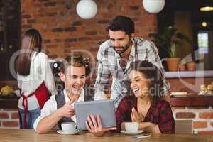 Smiling friends looking at digital tablet