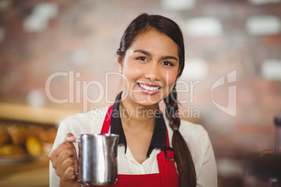 Smiling barista holding a milk jug