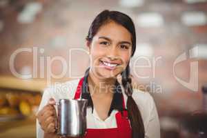 Smiling barista holding a milk jug
