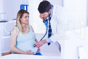 Doctor examining stomach of pregnant patient