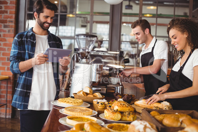 Smiling colleagues serving customer with tablet