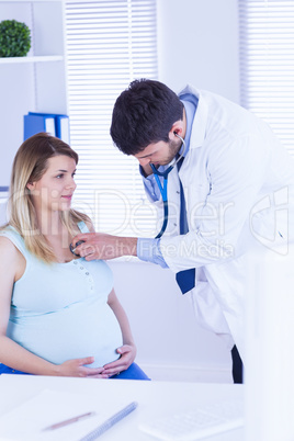 Doctor examining chest of pregnant patient