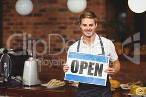 Handsome waiter presenting open sign