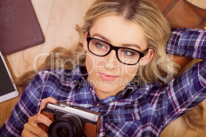 A blonde hipster lying on the floor taking a photo