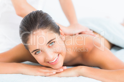 Pretty brunette enjoying a massage smiling at camera