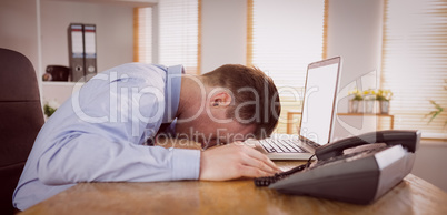 Stressed businessman with head on laptop