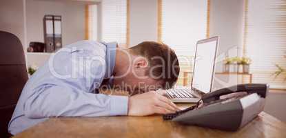 Stressed businessman with head on laptop
