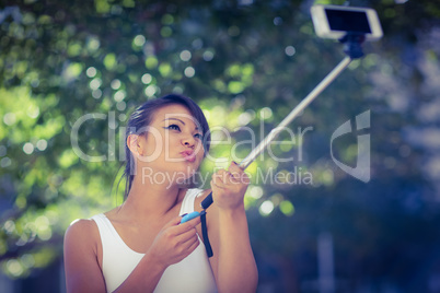 Smiling athletic woman taking selfies with selfiestick