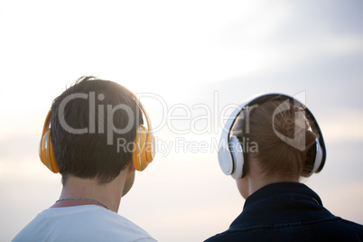 Young people in headphones enjoying music outdoor