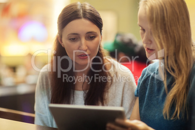 Two women have a discussion in the restaurant using electronic tablet