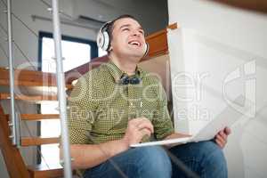 Excited hipster man relaxing with music and laptop