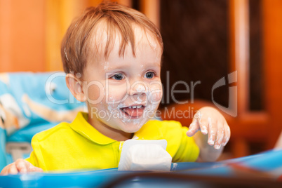 Happy child dirty with cream yoghurt