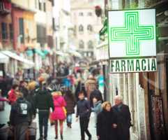 Pharmacy sign hanging on the building in crowded street