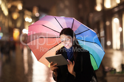 Woman using pad under umbrella in the evening city