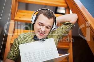 Man entertaining with laptop and music at home