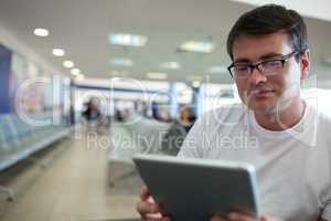 Man reading on tablet PC while waiting at the airport