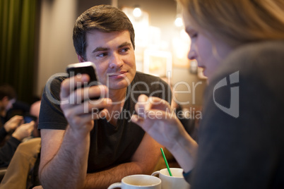 Man using mobile phone during meeting with girl in cafe