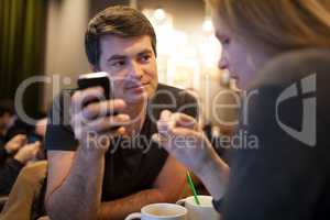 Man using mobile phone during meeting with girl in cafe