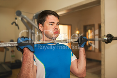 Strong young man exercising with barbell