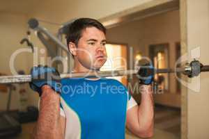 Strong young man exercising with barbell