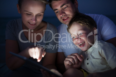 Parents and son with tablet PC outdoor late in the evening