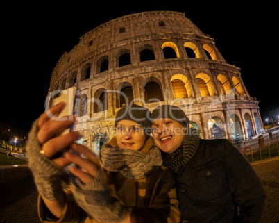 Happy couple making selfie by Coliseum at night