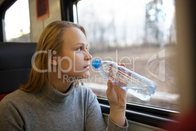 Woman drinking water and looking out train window