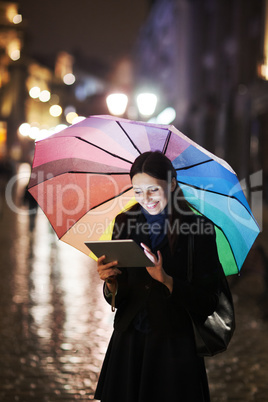 Brunette woman using tablet on the street on rainy day