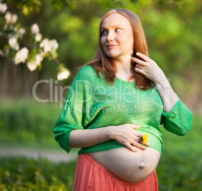 Pregnant woman in the light of evening sun outdoor