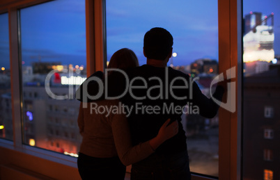 Couple embracing and looking at evening city together