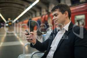Businessman with smartphone in subway