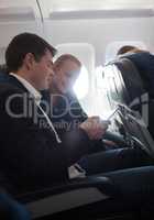 Young man and woman using cell phone in plane