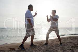 Two men having boxing training on the beach