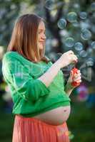 Pregnant woman blowing bubbles outdoor