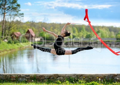 Rhythmic gymnast girl exercising with ribbon outdoor