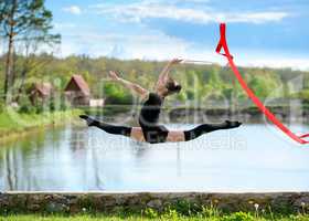 Rhythmic gymnast girl exercising with ribbon outdoor